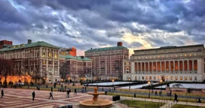 繁體中文 (Traditional Chinese): 美國哥倫比亞大學 Columbia University 晨邊高地校區 Morningside Campus 黃昏全景與圖書館建築,適合計劃透過 Common App 系統申請美國常春藤盟校、紐約留學或商科法律的海外精英學生作為選校參考。 簡體中文 (Simplified Chinese): 美国哥伦比亚大学 Columbia University 晨边高地校区 Morningside Campus 黄昏全景与图书馆建筑,适合计划透过 Common App 系统申请美国常春藤盟校、纽约留学或商科法律的海外精英学生作为选校参考。 英文 (English): A panoramic dusk view of the Columbia University Morningside Heights campus and historic library buildings in New York City, perfect for international students planning their Ivy League university admissions strategy.